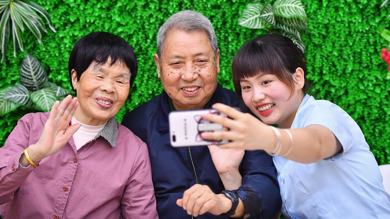 Liu Meng (right) teaches residents how to shoot video on a smartphone at an elderly care service centre (Xinhua/Chen Zeguo)